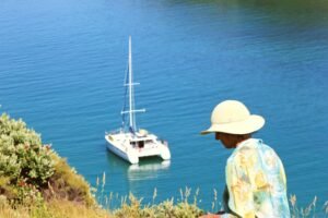 Woman walking on Waewaetorea island in Bay of Islands with catamaran on private sailing charter
