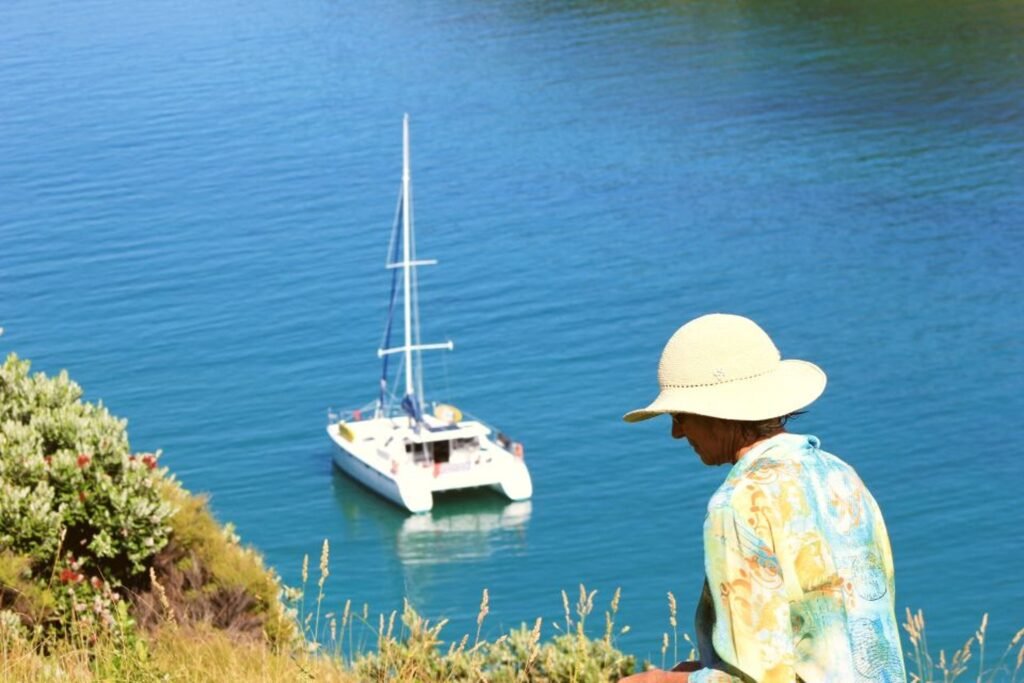 Guest walking on shore with sailing boat anchored in a remote Bay of Islands bay