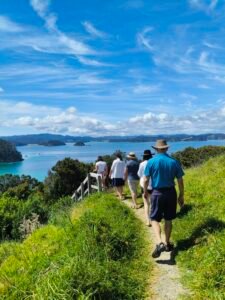 Guests hiking on Motuarohia / Roberton Island with panoramic Bay of Islands views during a sailing charter