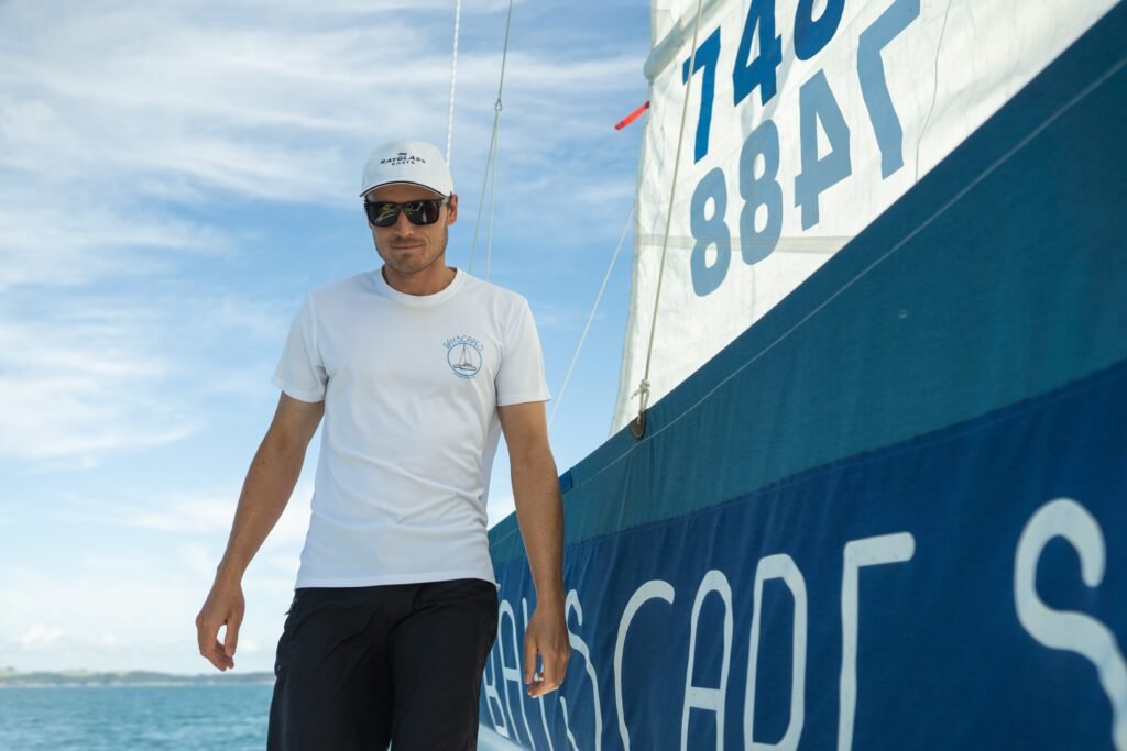 A crew member from Bayscapes Sailing Charters walks on a boat, assisting with the sails during a sailing trip.