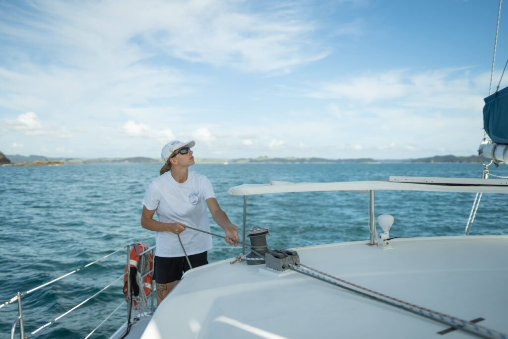 A crew member from Bayscapes Sailing Charters assists with sails from the helm area of a catamaran