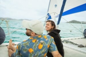 two friends relax on a catamaran with a full day sailing charter