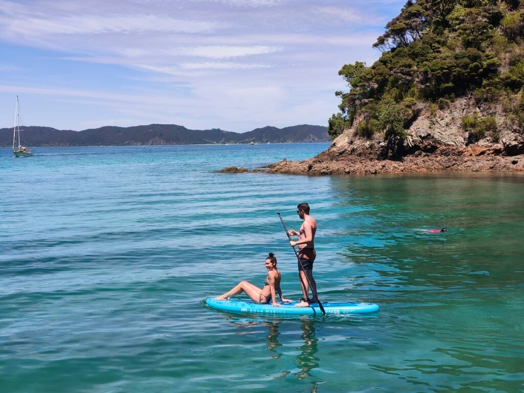 Guest paddleboarding from a catamaran in calm ocean water